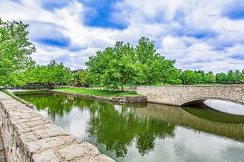 A stone wall borders a body of water with a bridge crossing over it.